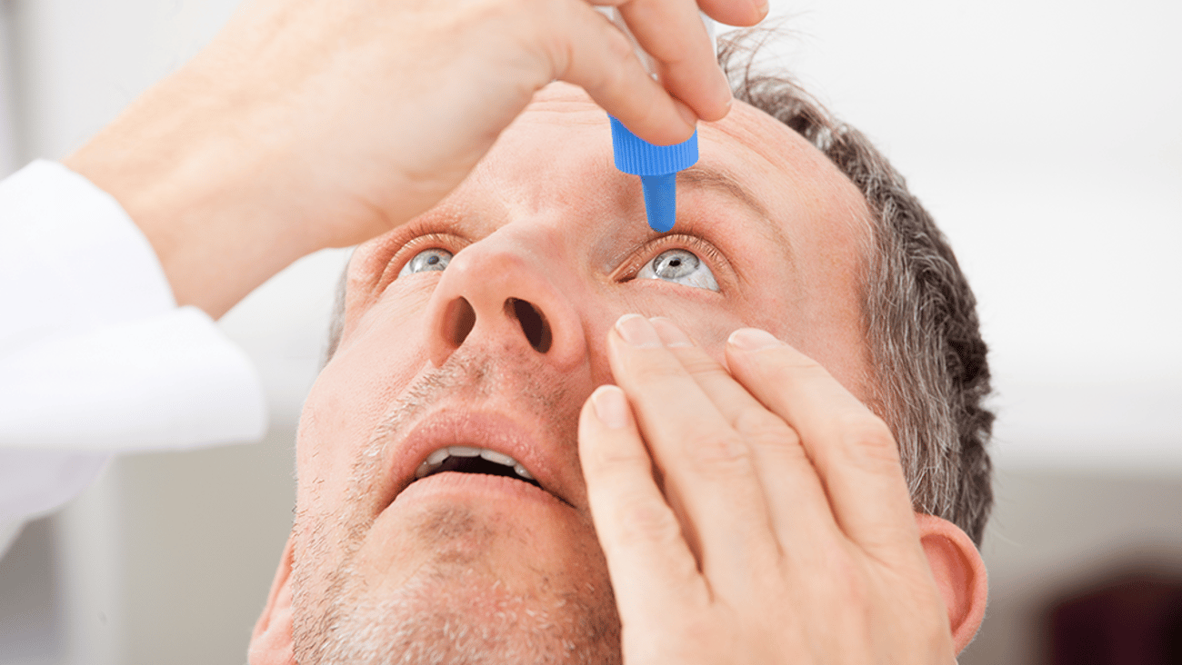 middle-aged Caucasian man putting drops in his eye