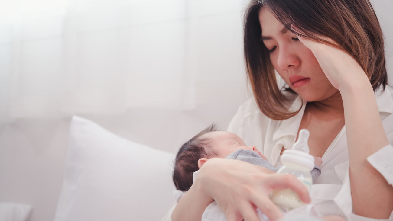 A woman with baby appears tired and stressed.