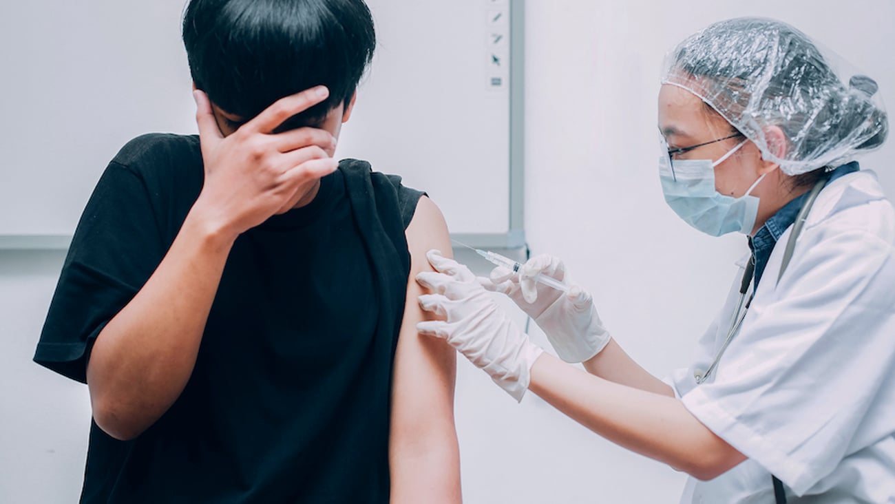 Young man getting vaccine covers face