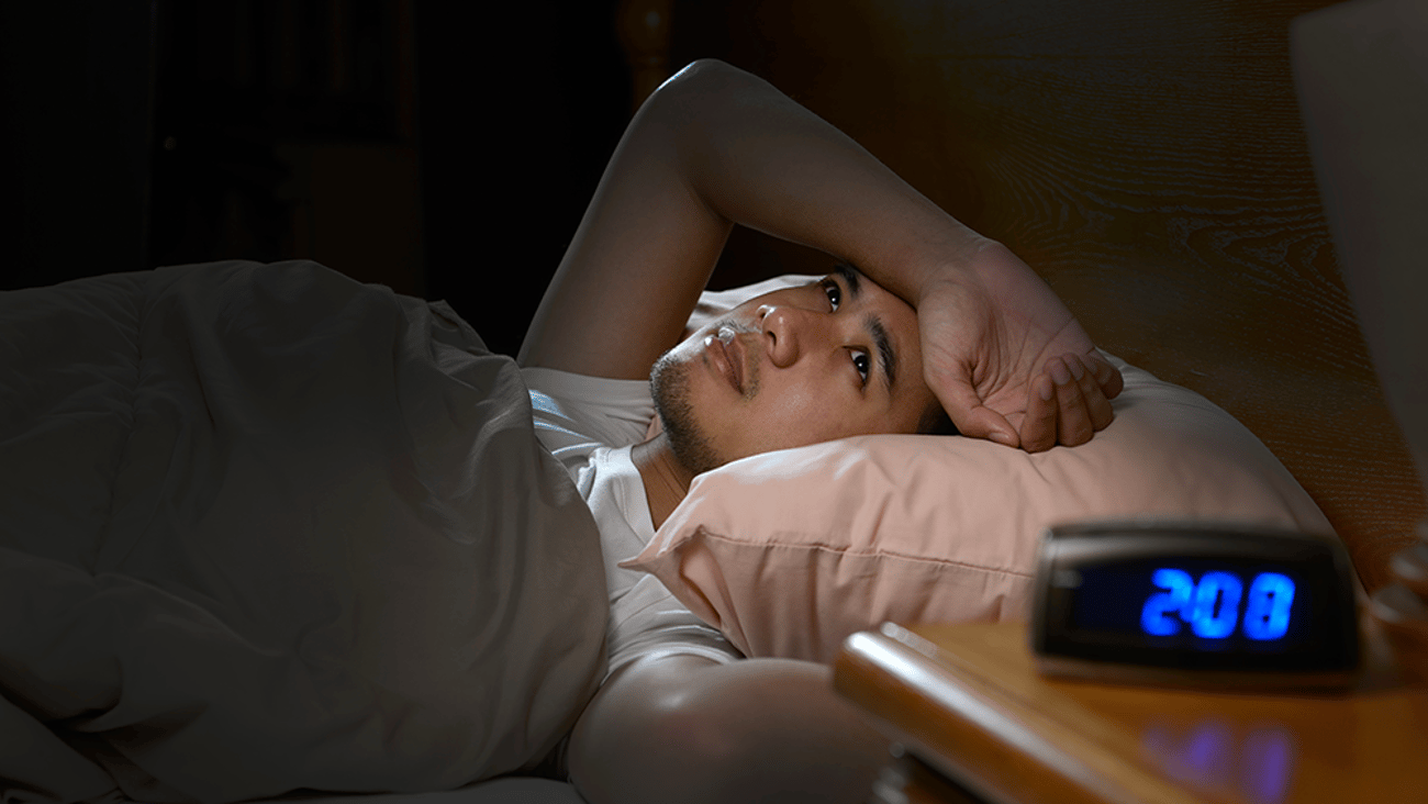 young Asian man lying awake in bed in the middle of the night