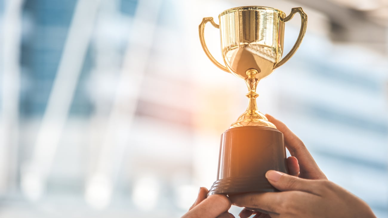 A pair of hands holds up a small trophy.