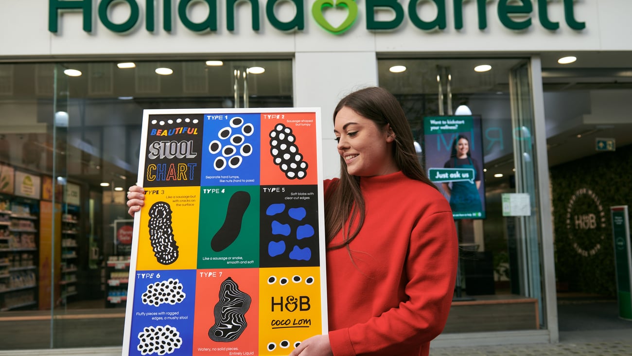 Artist Coco Lom holds up her poster outside a store.