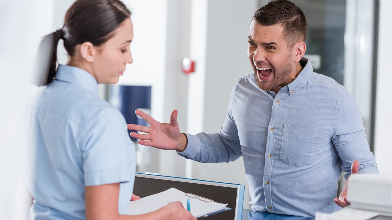 Angry male patient with female healthcare worker.