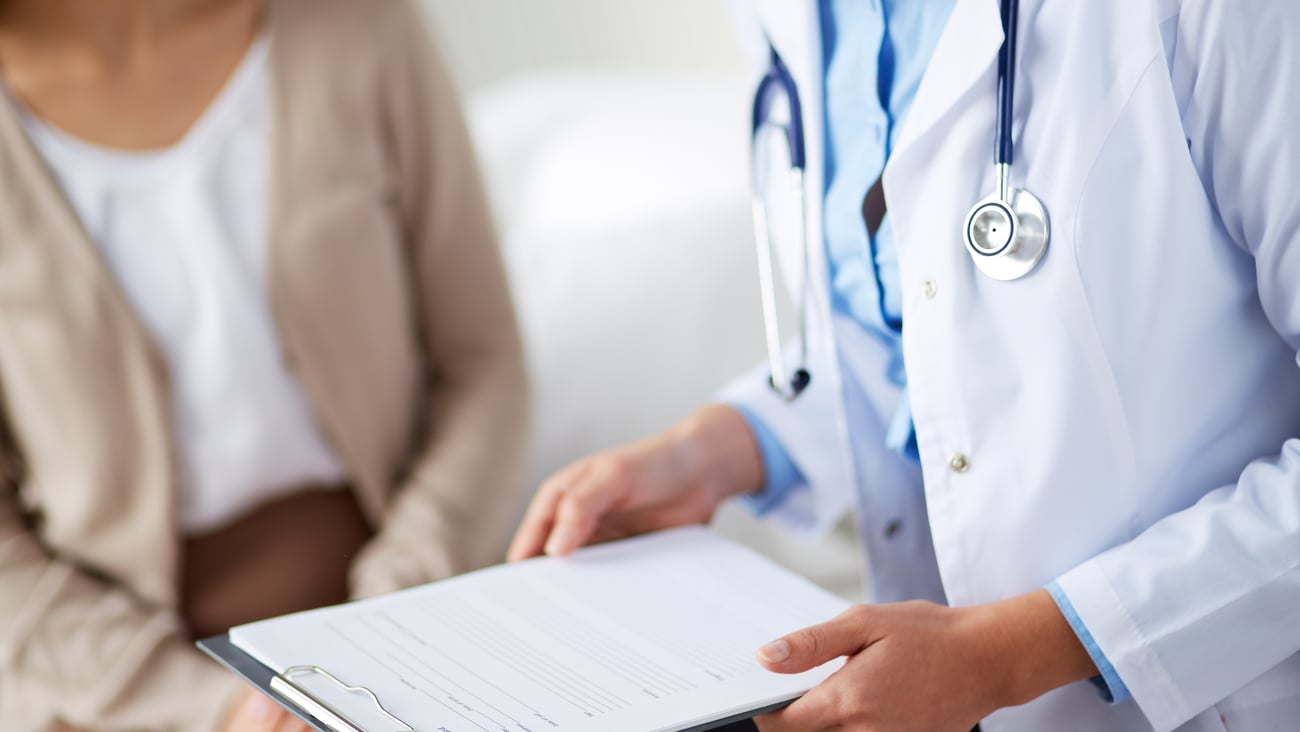 Doctor holding clipboard speaking with a patient