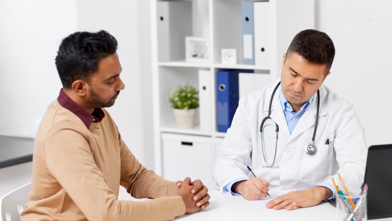 Patient watching doctor write a prescription