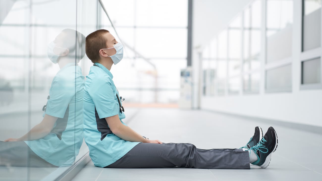 Exhausted doctor sitting by the side of a wall