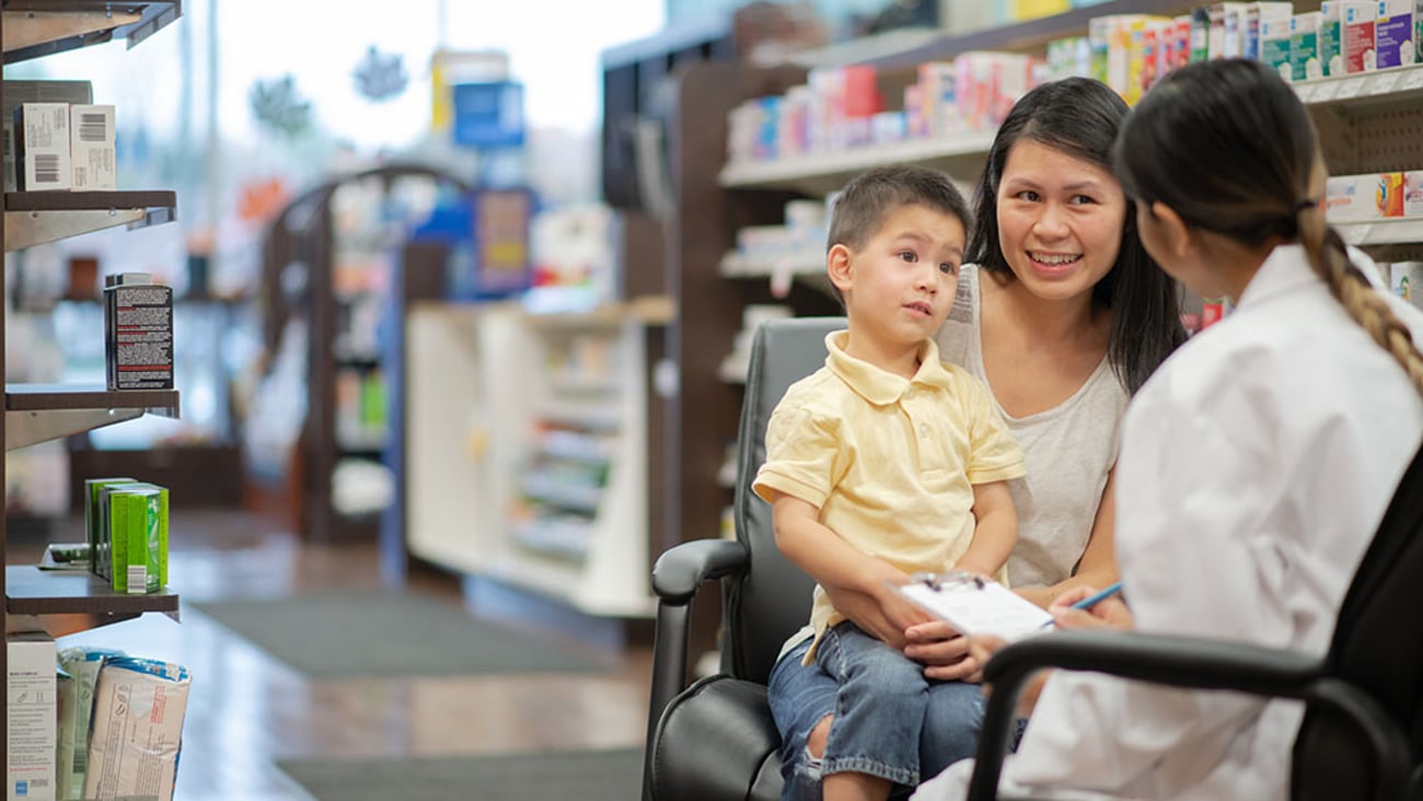 a mother and young child discuss their health with a pharmacist