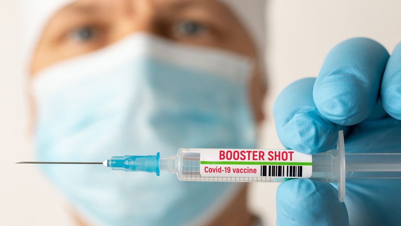 healthcare worker holding a needle containing a COVID-19 booster shot