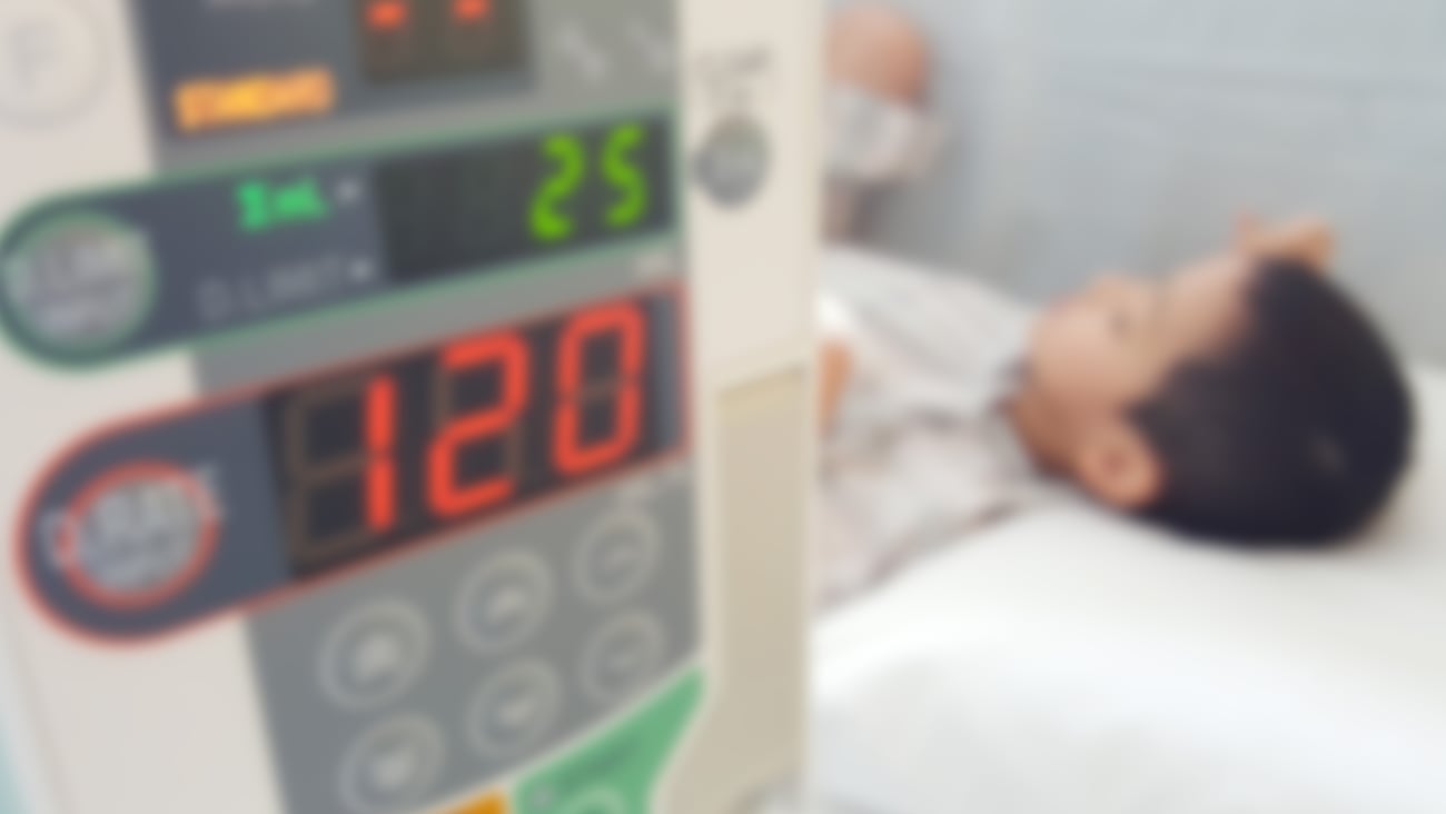 Young boy lying in a hospital bed with a heart monitor in the foreground