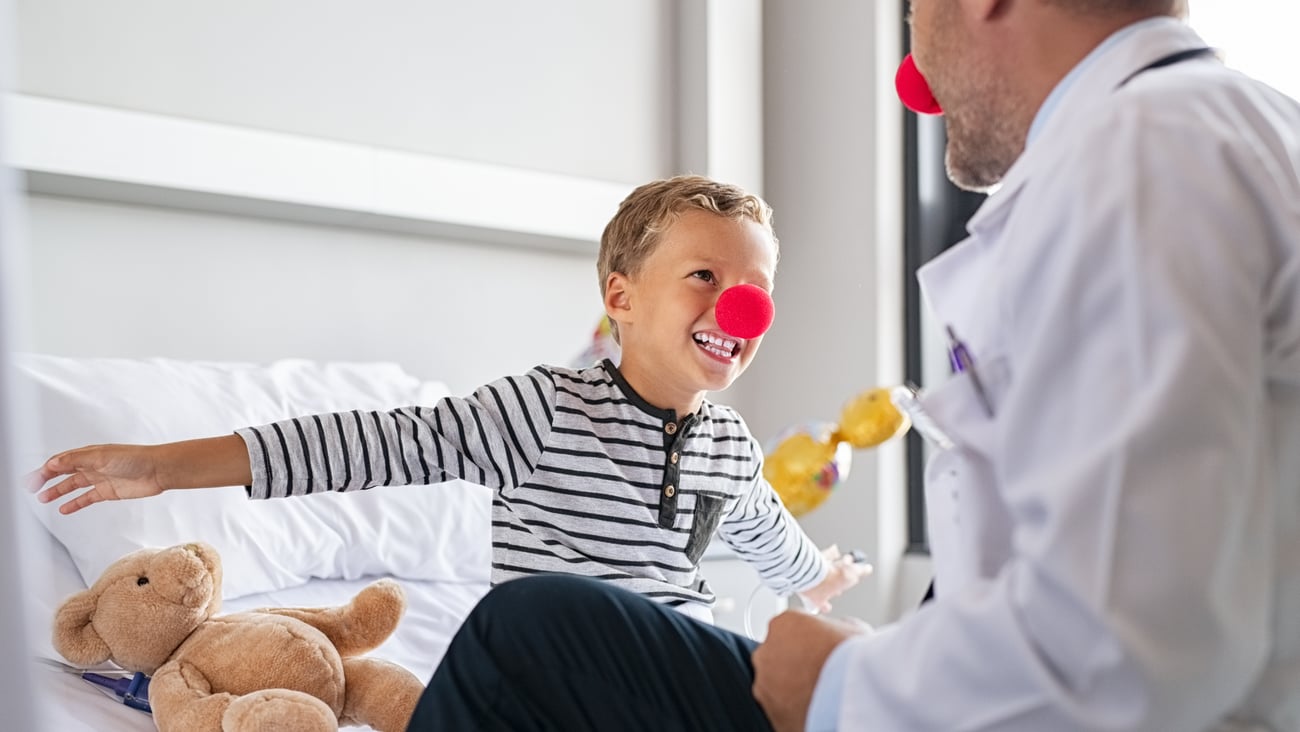 Doctor joking with a young patient, both wearing red noses