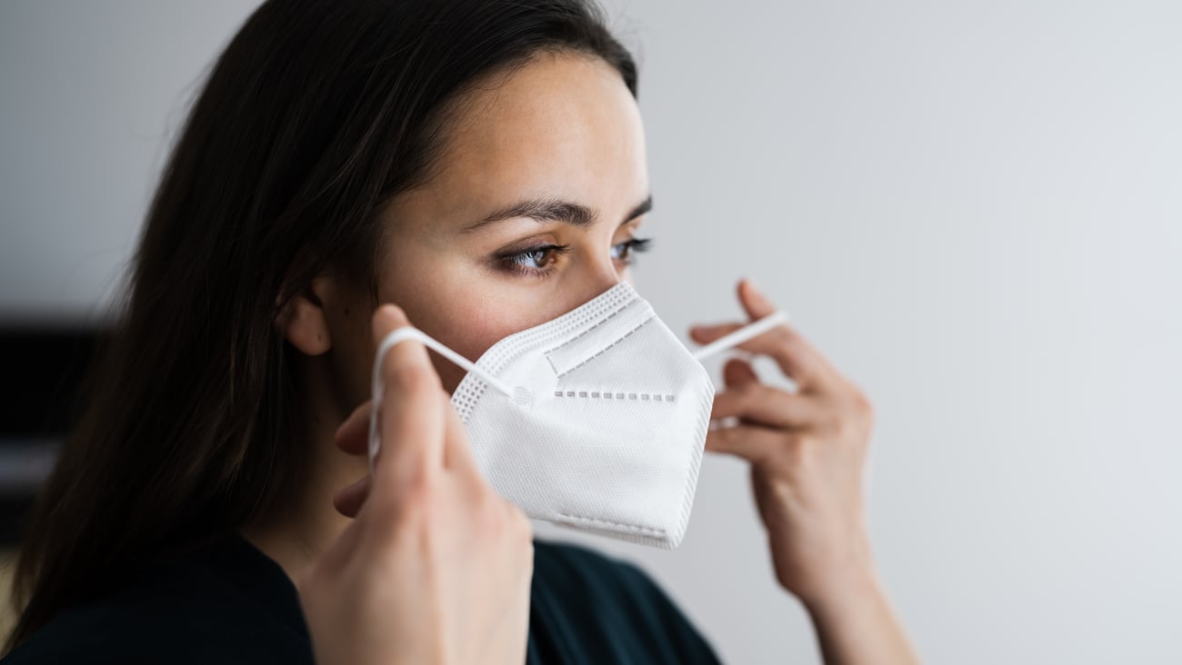 Woman putting on N95 mask