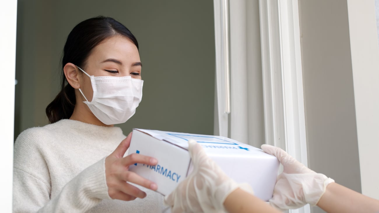 Young woman wearing mask receiving a pharmacy package 