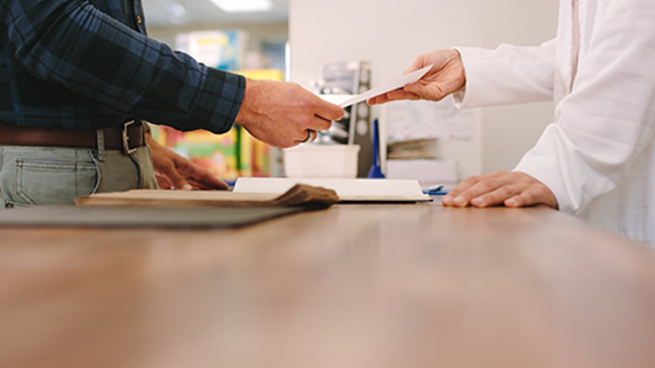 A pharmacist hands a patient a receipt