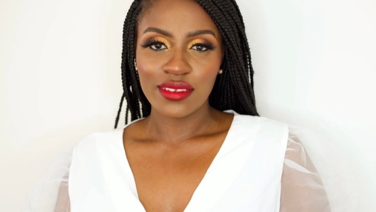 A Black woman poses in front of a white background