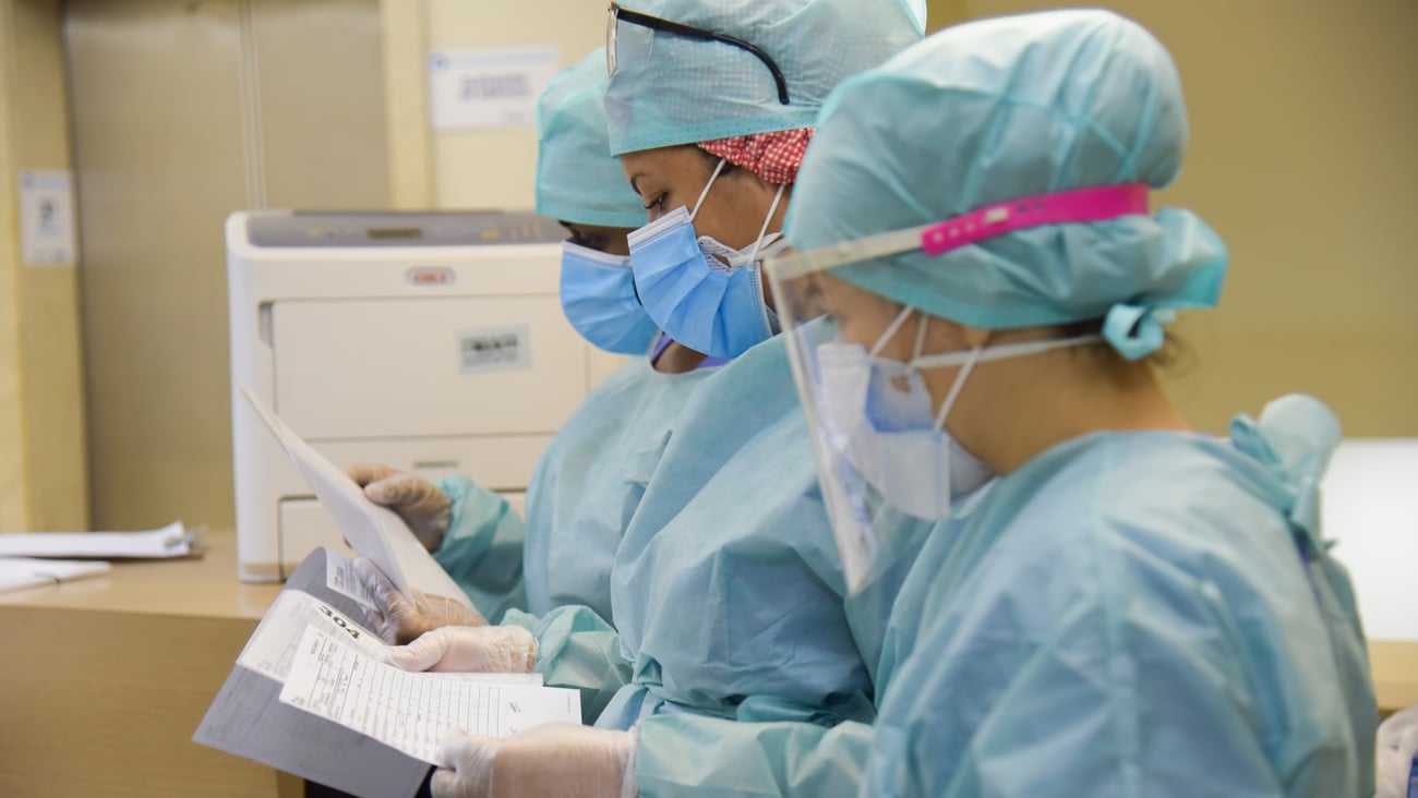 nurses looking at paperwork, wearing full PPE 