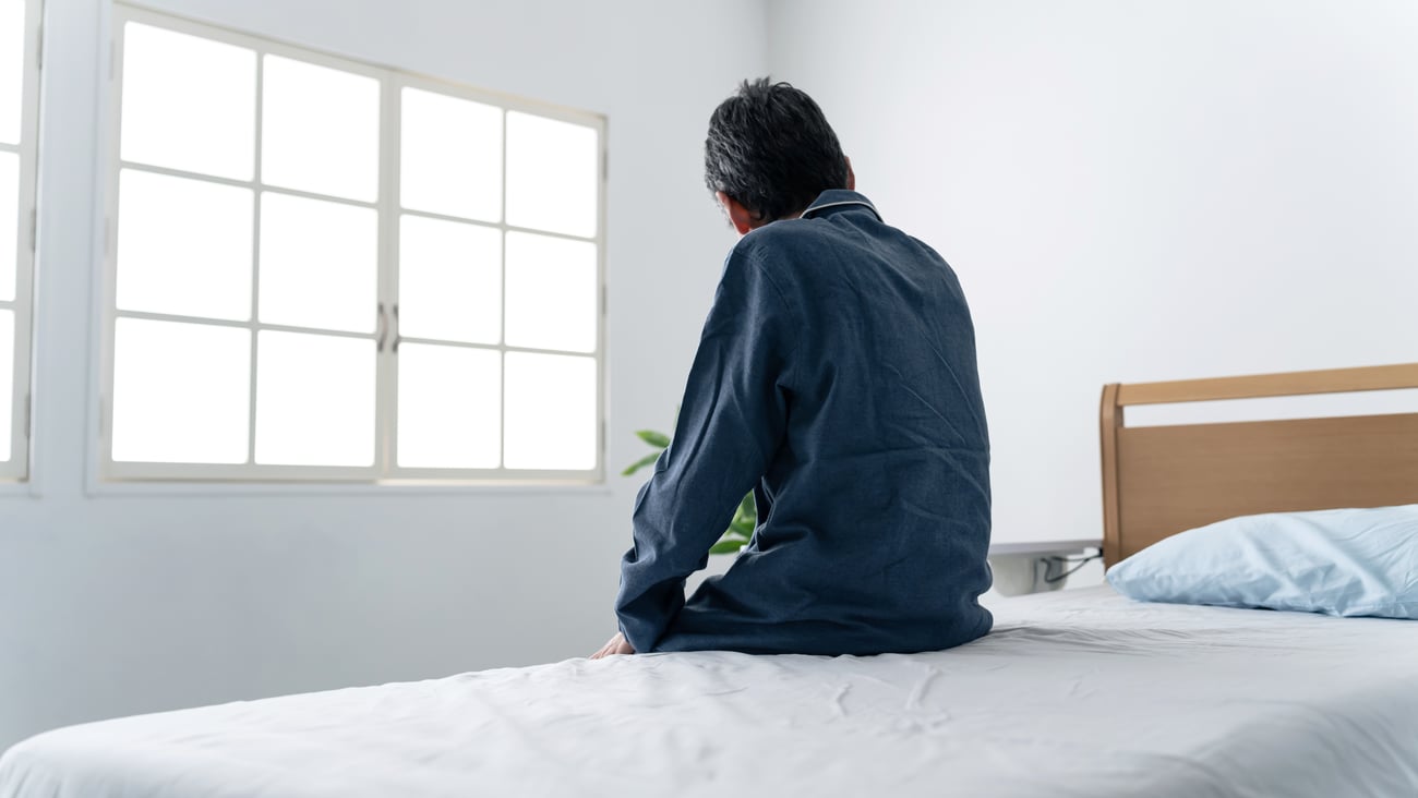 Man sitting on the bed looking at a window