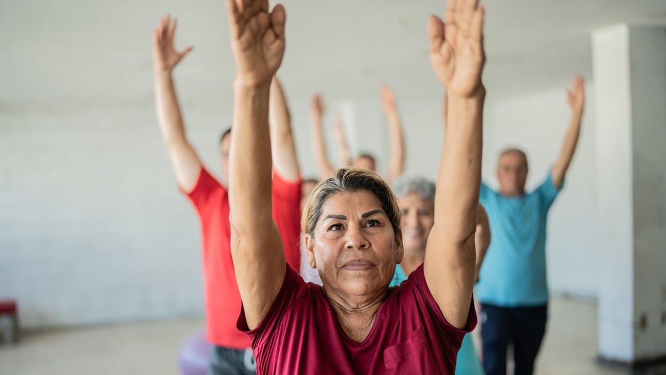 Group of older people doing yoga with their arms in the air