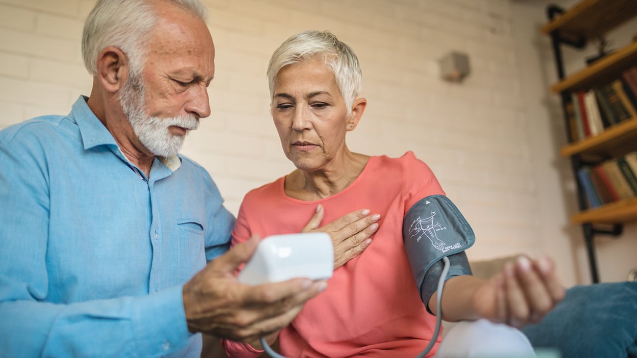 Husband helping his wife read a blood pressure monitor