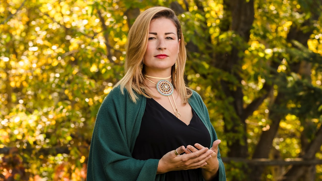 A woman standing tall with a green shawl on her shoulders