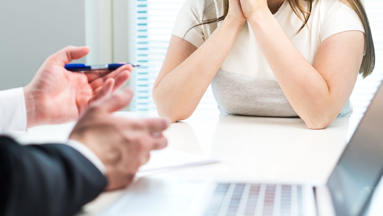 two people sitting at desk, just hands and upper body showing, hands suggest difficult conversation