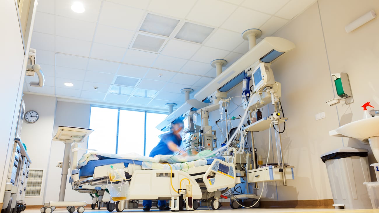 Hospital room with bed and healthcare worker helping patient