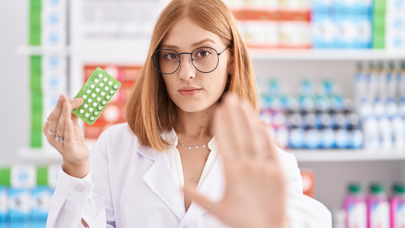 Young woman pharmacist holding out her hand to signal 'stop'