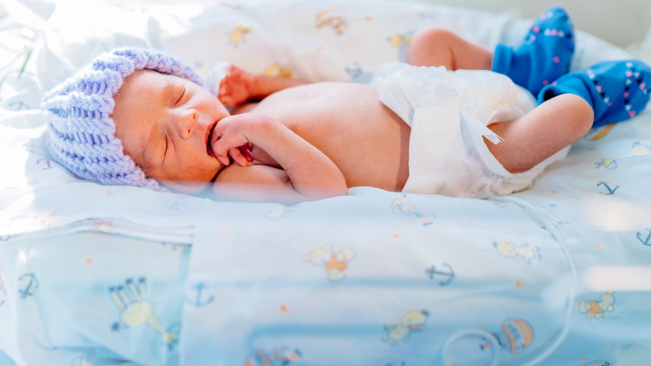 premature baby birth in hospital bed wearing a cap and booties