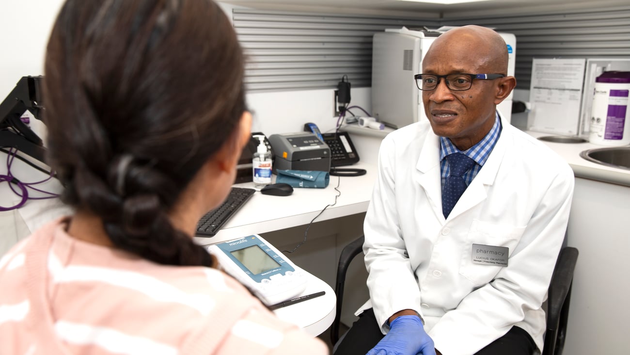 Black male pharmacist talking to a white brunette woman patient about cardiovascular disease