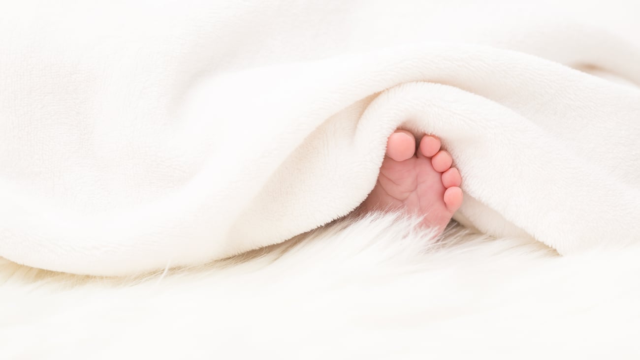 baby foot peeking out from white blanket
