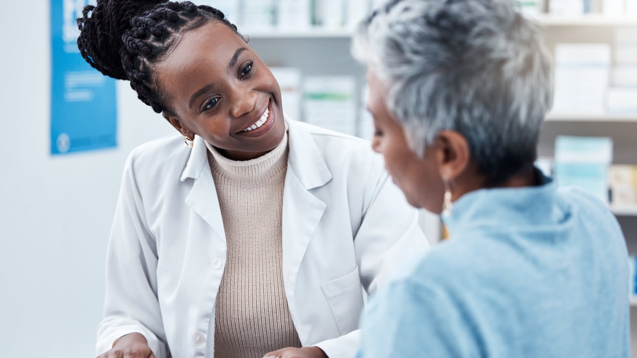 Black female pharmacist smiling with black older woman patient