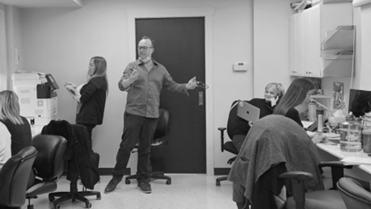 Black and white photo of Dr. John O'Mahony surrounded by his staff