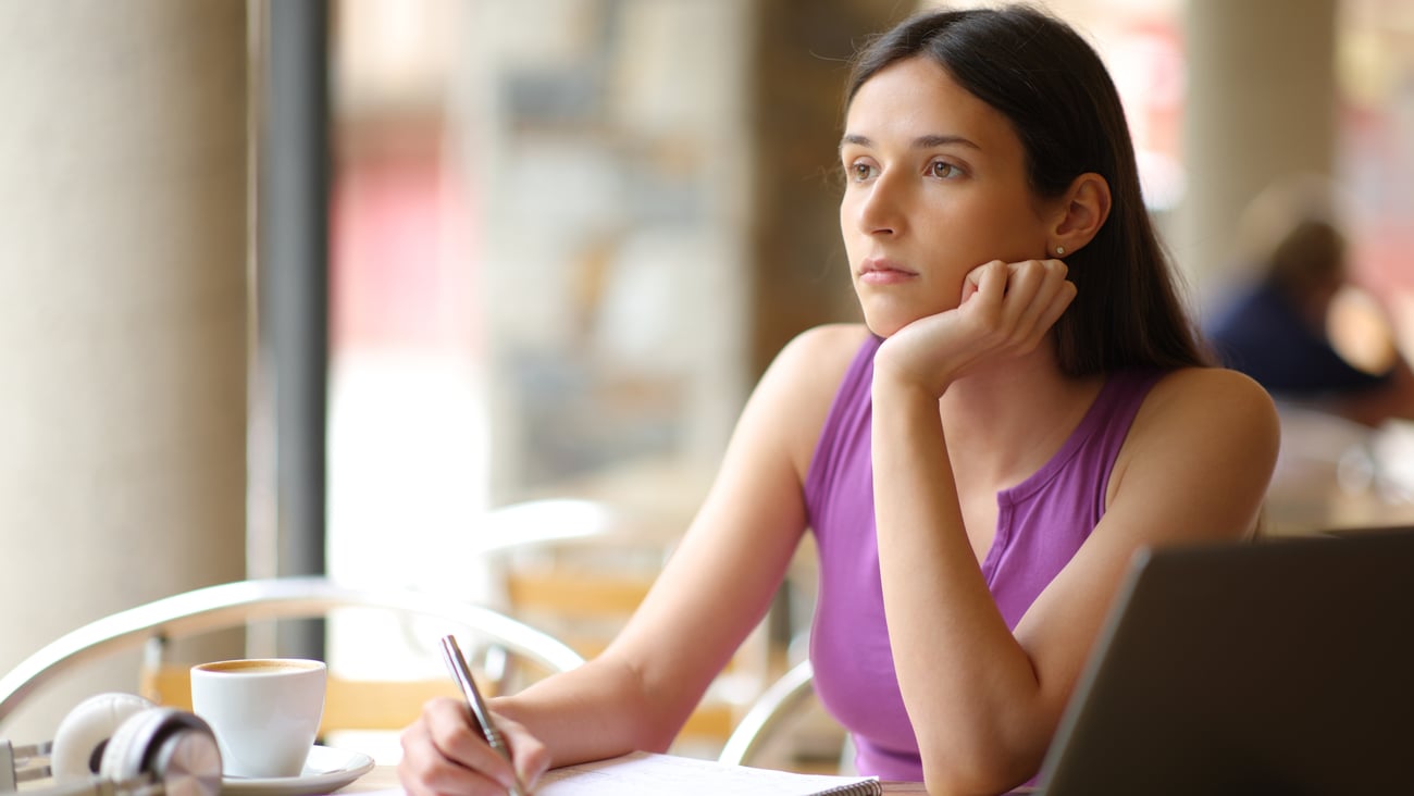 Caucasion woman sitting in a cafe, gazing off into the distance