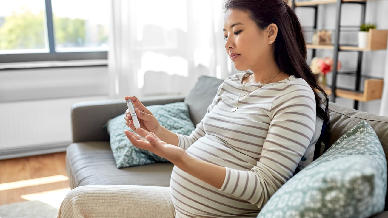 Young pregnant Asian woman using a pen device to administer diabetes treatment