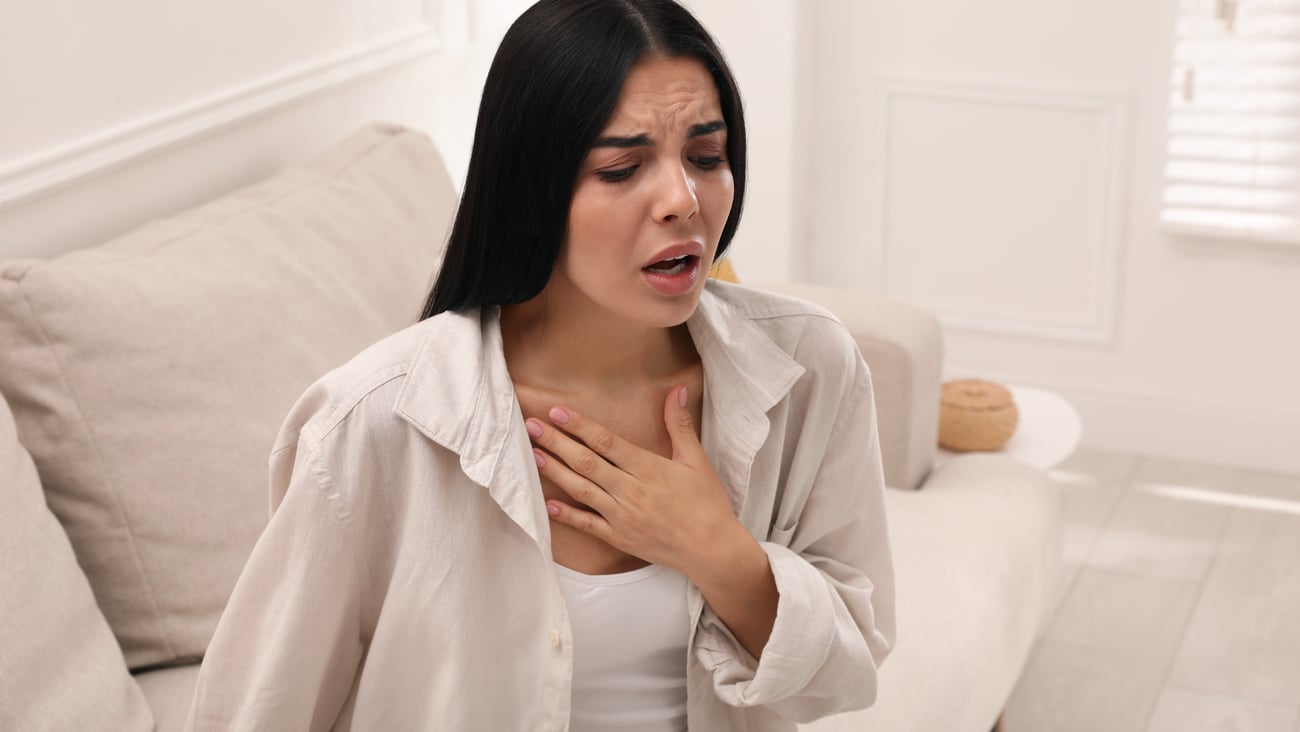 Young woman sitting on her bed struggling for breath