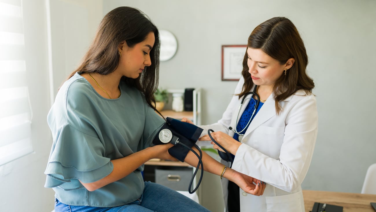 Young white woman getting her blood pressure checked by her doctor