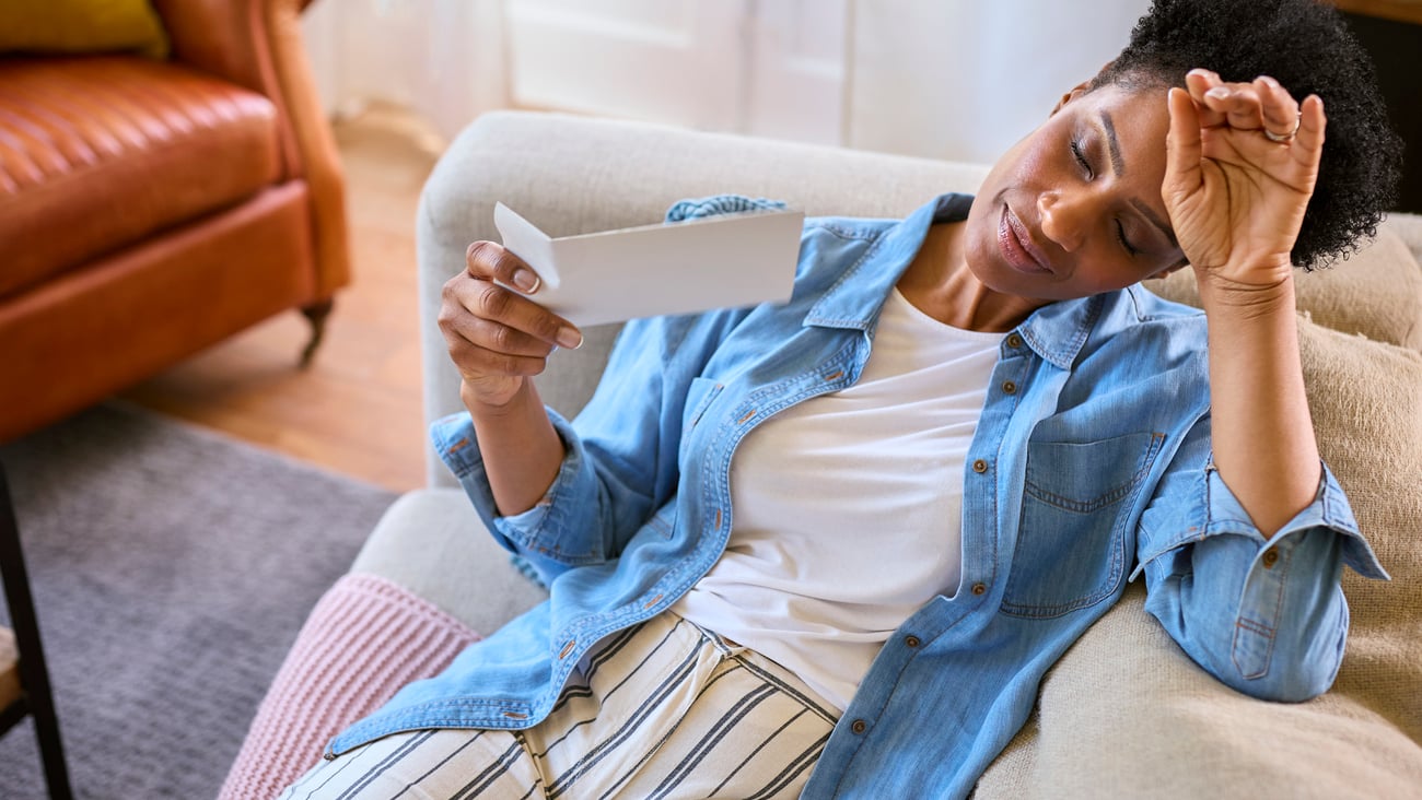Woman experiencing a hot flash as she lies down on sofa