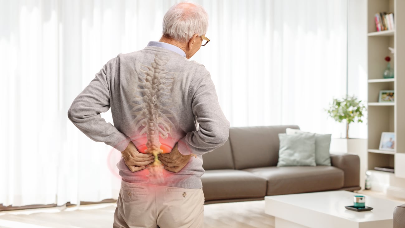 Older man holding his back with both hands due to acute kidney pain