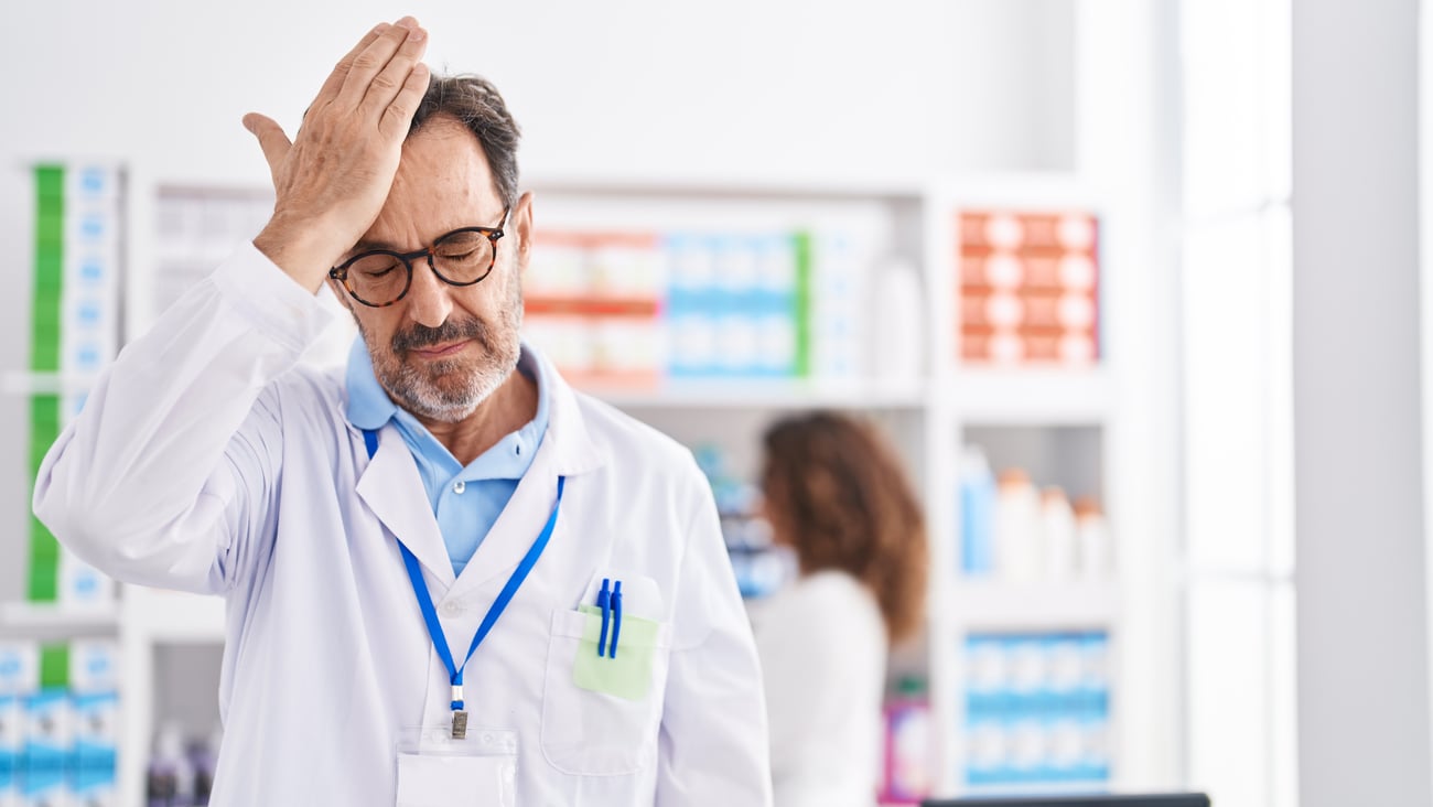 white mail pharmacist holding hand to head