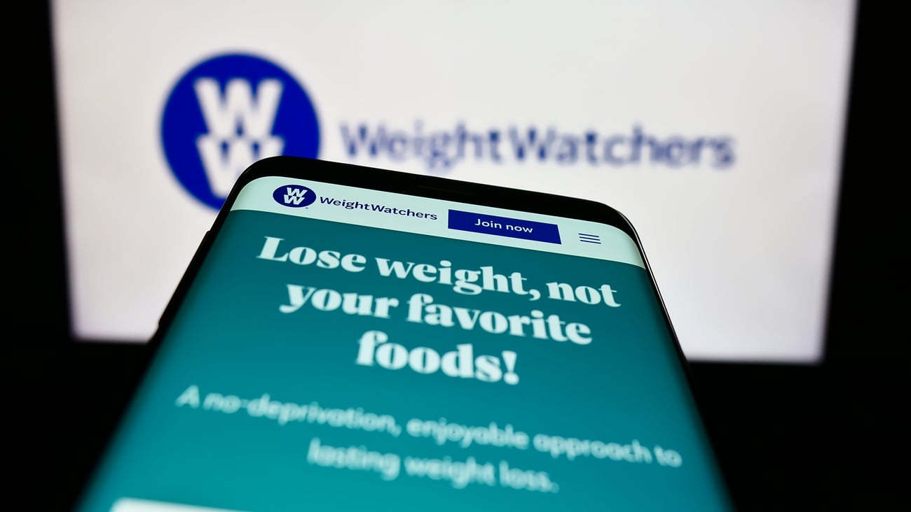 Smartphone with website of WW International Inc. (Weight Watchers) on screen in front of business logo.