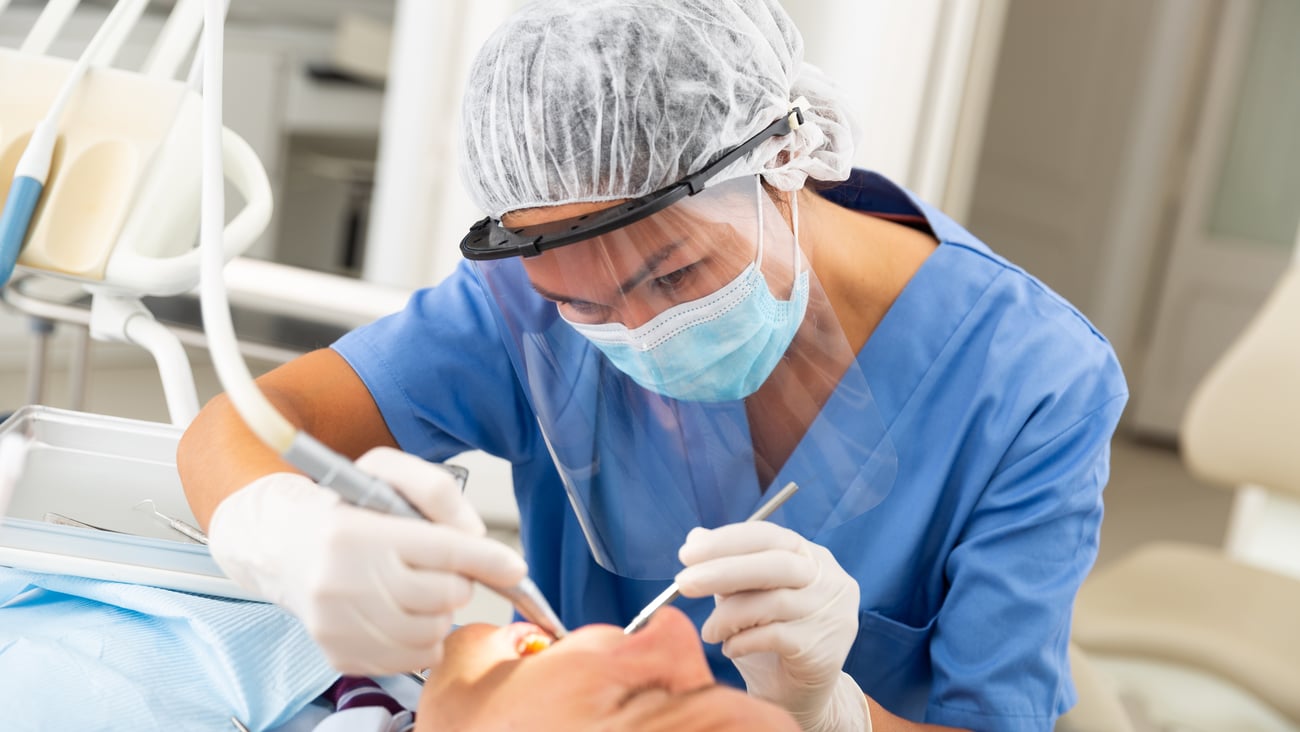 Dentist professional filling teeth for man patient sitting in medical chair