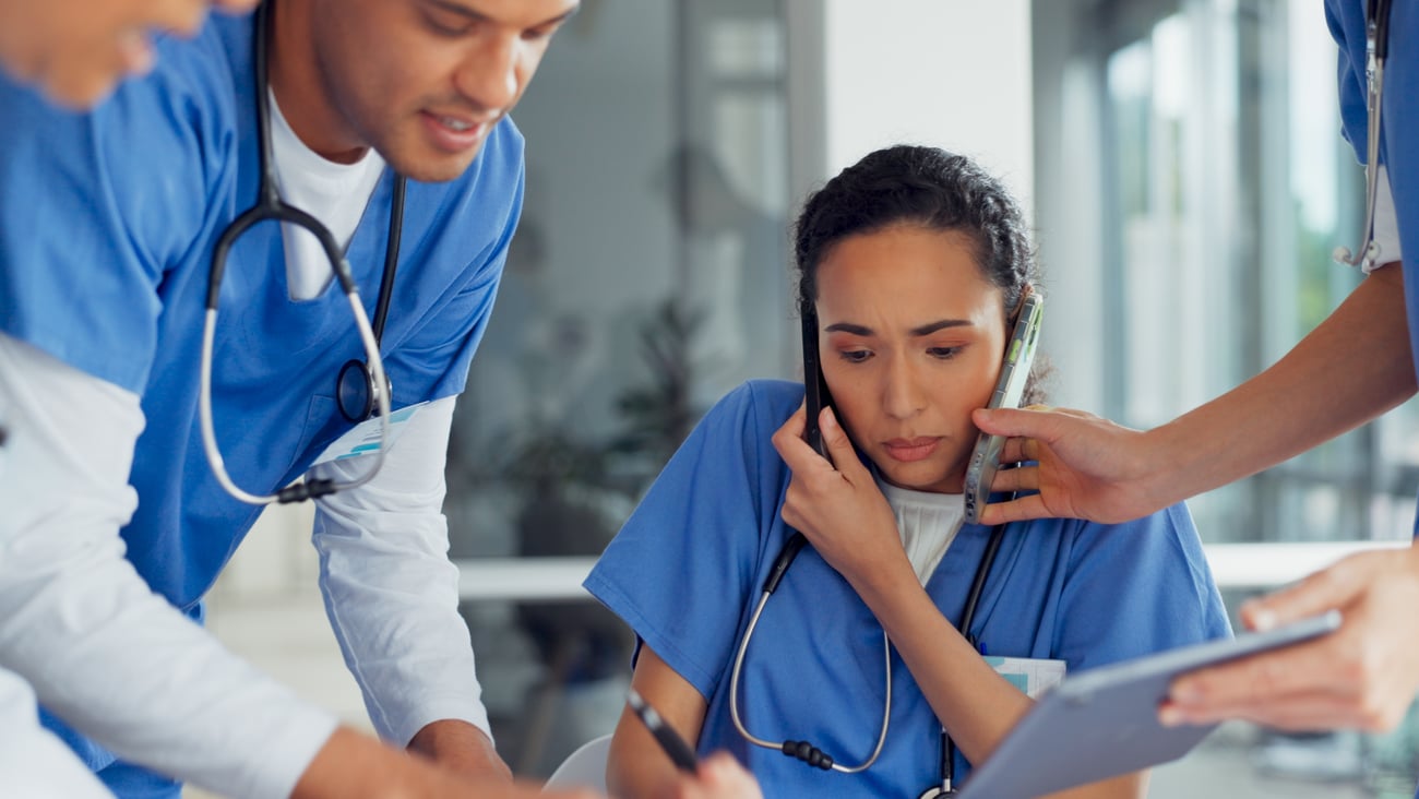 Young woman doctors overwhelmed by several colleagues trying to talk to her at once
