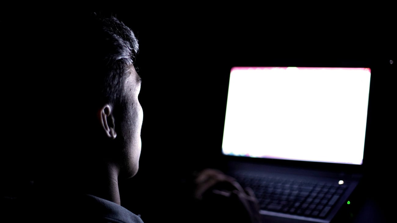 A young man in front of a computer late at night.