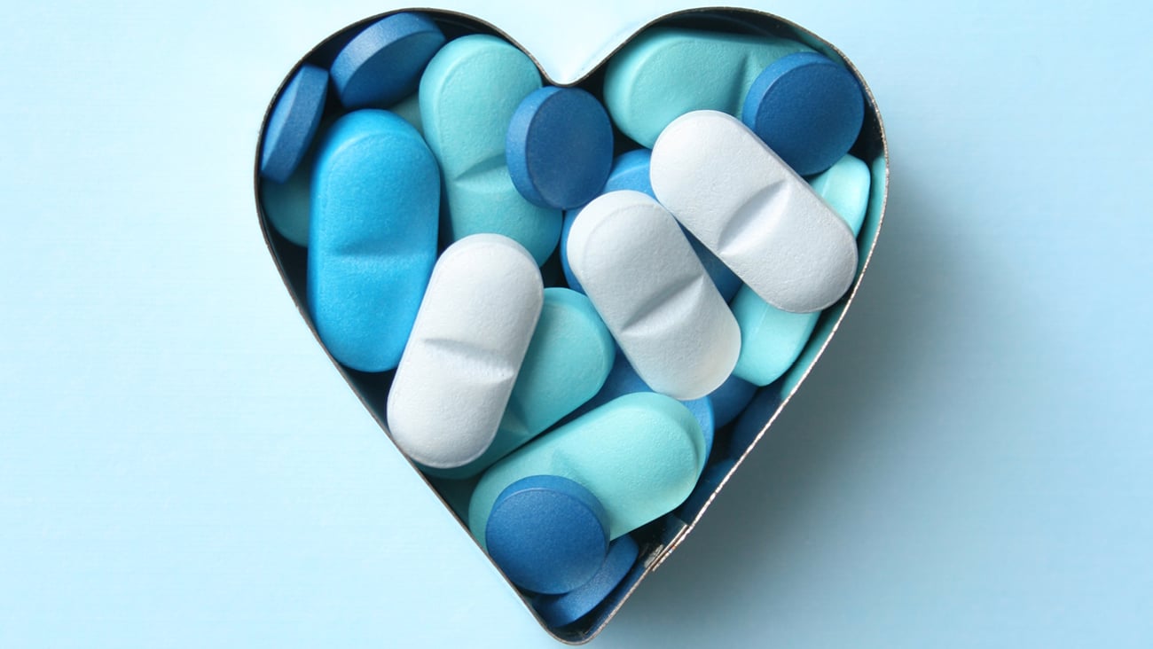 A heart shaped tin full of white and blue pills