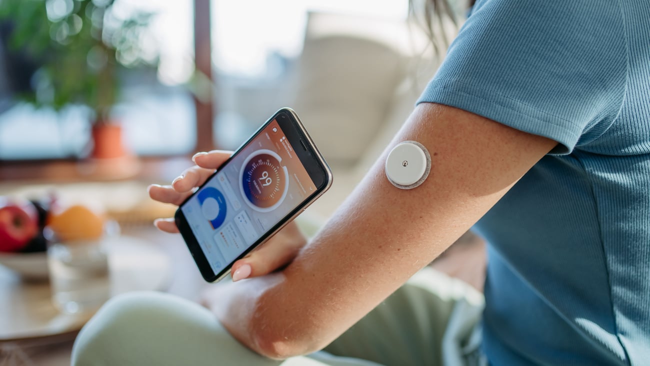 Woman with diabetes checking blood glucose level at home using continuous glucose monitor.