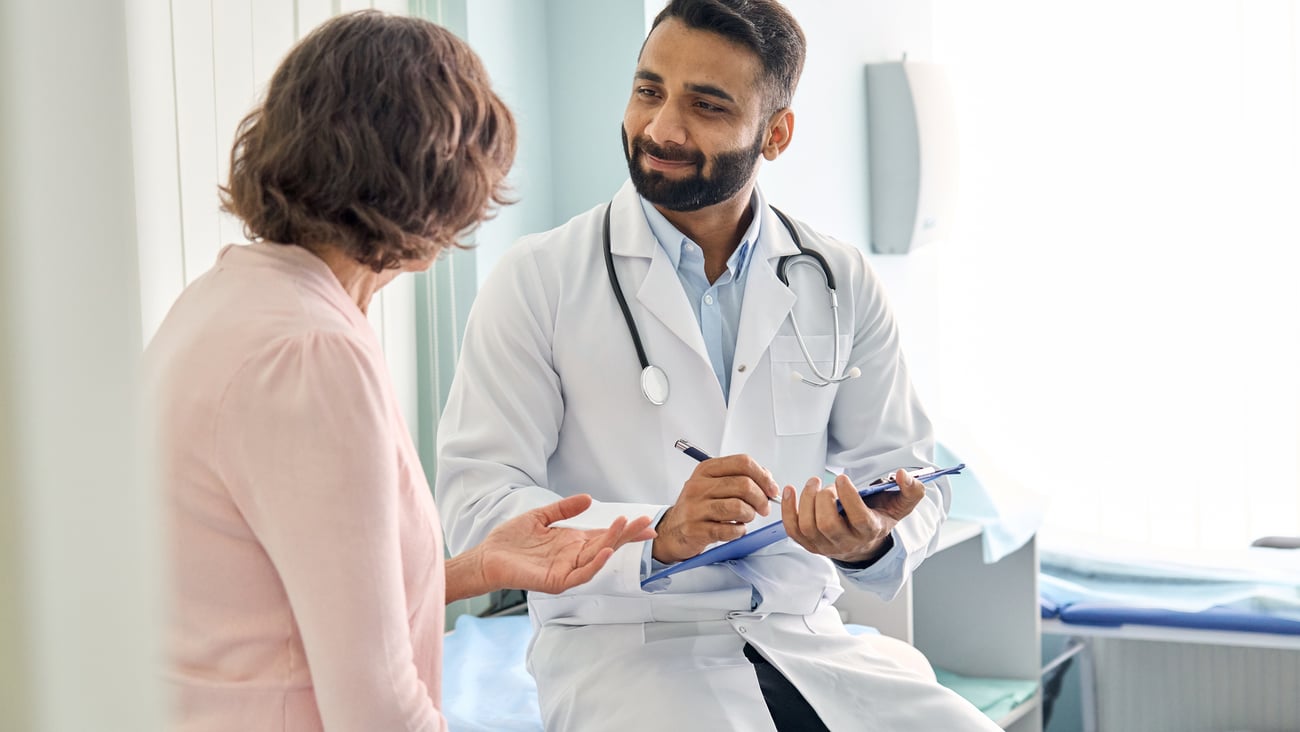 Young male doctor chatting with an older female patient in a clinic