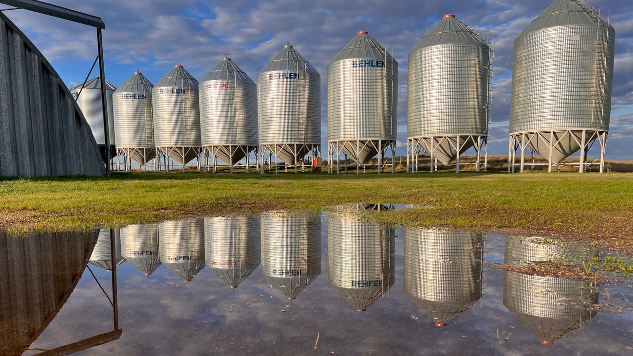 Grain bins reflected in puddle, lisa knudsen