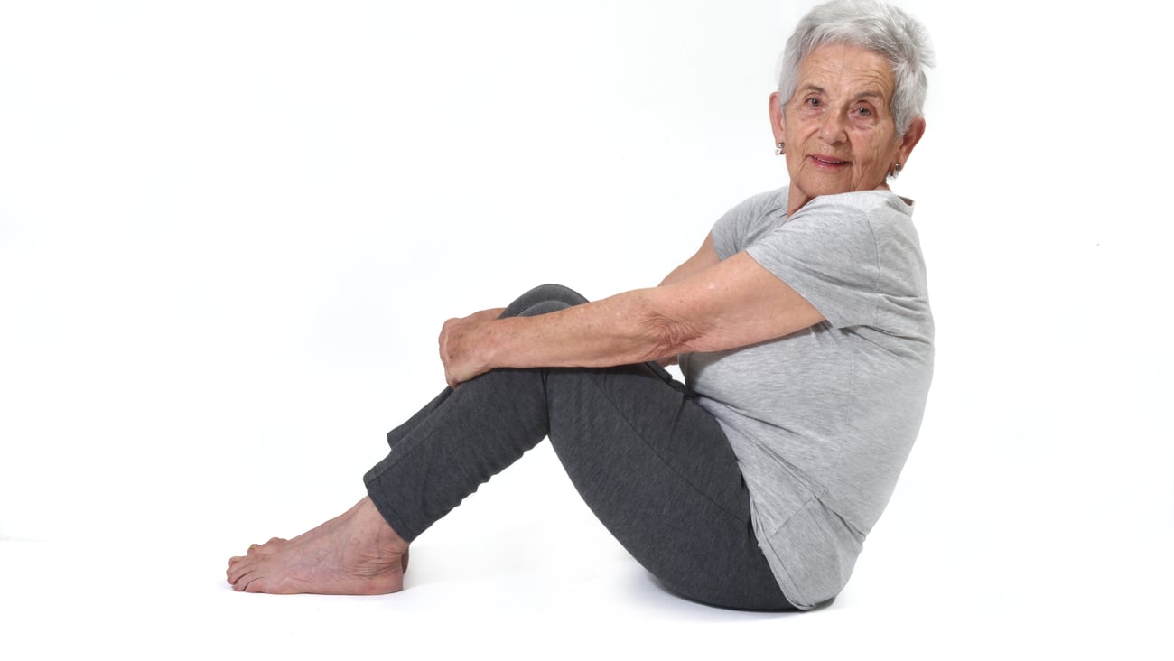 older white woman sitting on floor in profile, white background