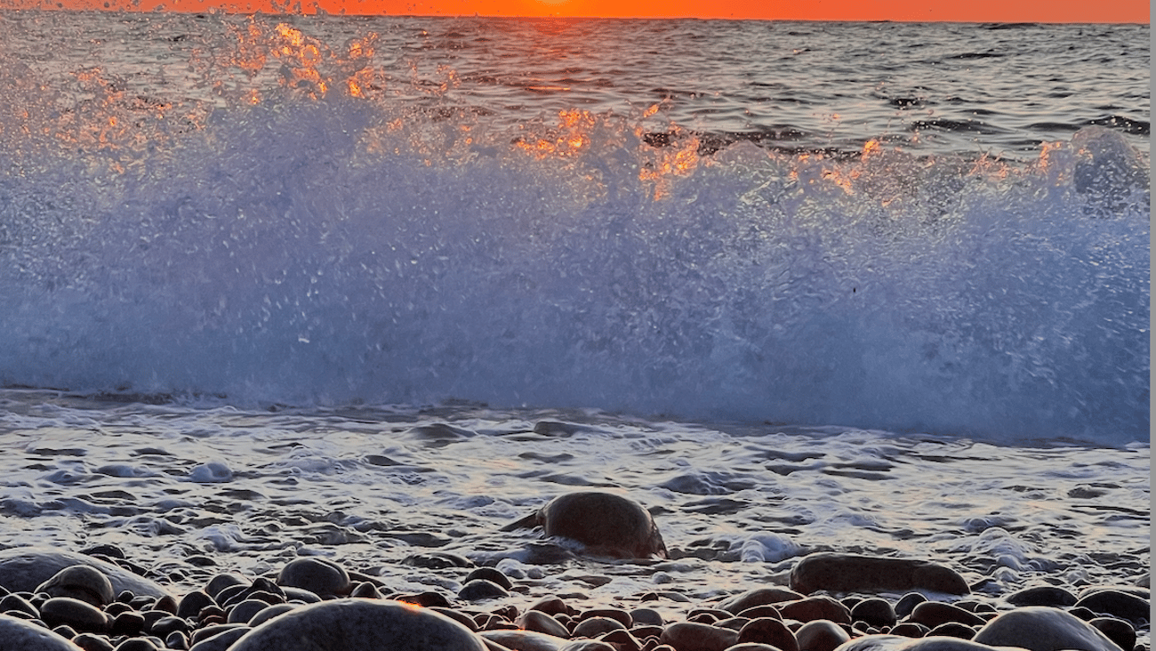 the sunset showing over a rocky beach