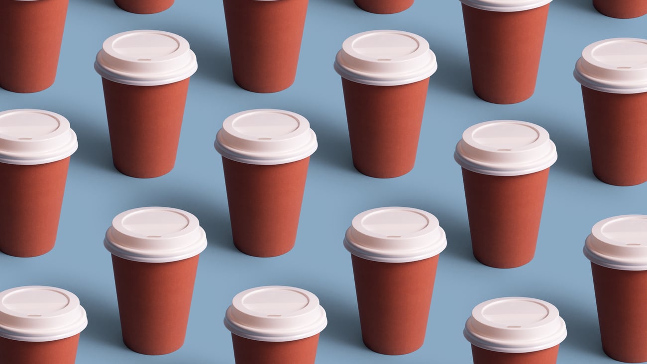 Multiple take out coffee cups against a blue background