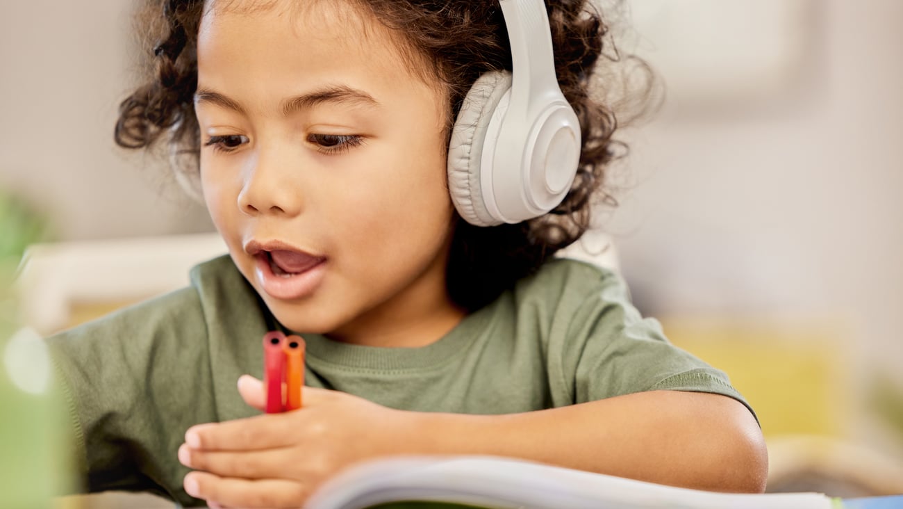 Young child with headphones drawing with crayons